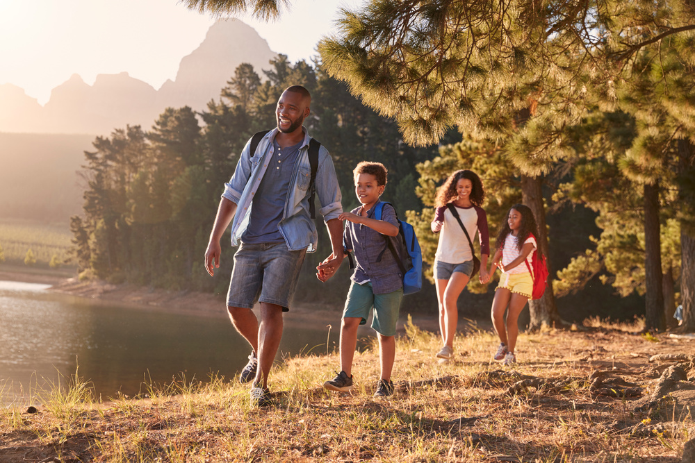 A young family of four hikes by a lake.