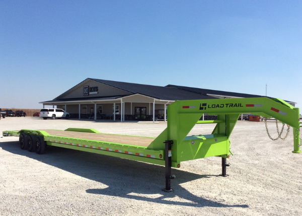 A green Load Trail gooseneck on the lot. Kate's Trailers building visible in the background.